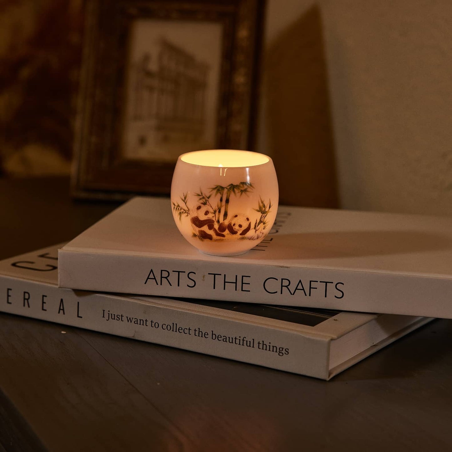 A shining translucent tealight candle holder of two pandas pattern stand on two books, you can see the candlelight through the translucent candle holder.