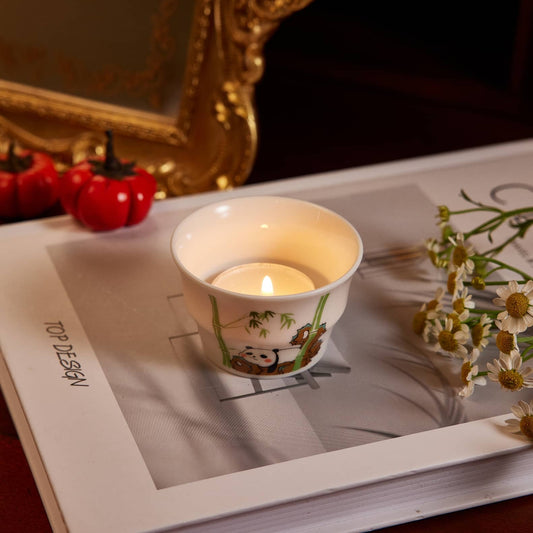 A tealight candle lighted in a bamboo shape tealight candle holder stand on a white book.